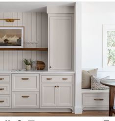 a kitchen with white cabinets and wood floors