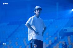 a man standing on top of a tennis court next to a blue light in the background