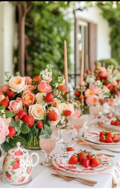 the table is set with pink and white flowers, candles, and teapots