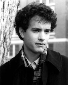 a young man standing next to a tree