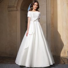 a woman in a white wedding dress posing for the camera with her hand on her hip