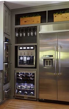 a stainless steel refrigerator in a kitchen with wooden flooring and cabinets on both sides