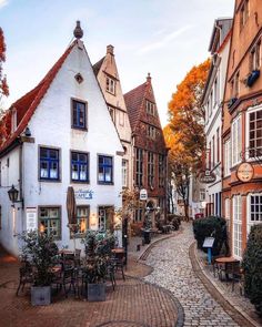 a cobblestone street in an old european town with white buildings and red tiled roofs