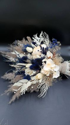 an arrangement of flowers and feathers on a black surface