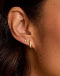 a close up of a woman's ear wearing gold hoop earrings with small diamonds