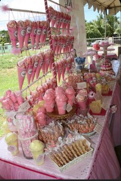 a pink table topped with lots of desserts and candy bar items on top of it