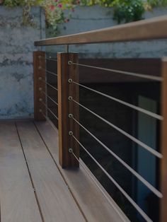 a wooden deck with metal railing and planters on the wall in the back ground