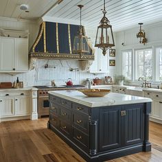 a large kitchen with an island in the middle and two chandeliers hanging from the ceiling