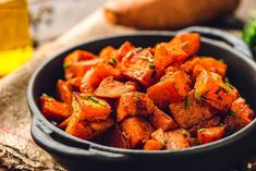 a bowl filled with cooked carrots on top of a table next to some bread