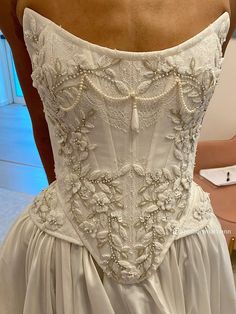 the back of a woman's wedding dress with beading and pearls on it