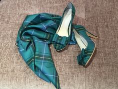 a pair of blue and green plaid shoes on top of a bed next to a scarf