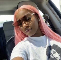 a woman with pink hair sitting in the back seat of a car wearing sunglasses and a bob marley t - shirt