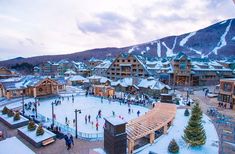 an aerial view of people skating on the ice rink in front of a mountain resort