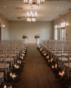 rows of chairs with flowers and candles on them in an empty room at a wedding