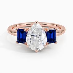 a three stone ring with an oval cut diamond and blue sapphire