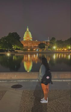 a woman is standing in front of the capitol building at night with her back turned to the camera