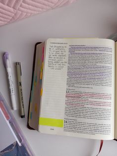 an open book sitting on top of a white table next to a pen and marker