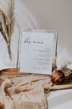 a table with a menu and some dried plants in a vase on top of it