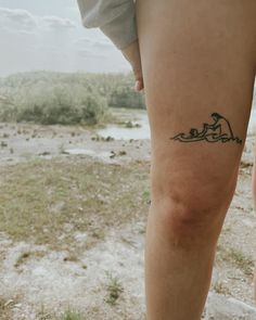 a person with a small tattoo on their leg standing in the grass and looking off into the distance