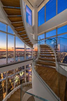 a spiral staircase in the middle of a room with large windows looking out onto a city