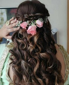 a woman with long brown hair and flowers in her hair is looking at the mirror