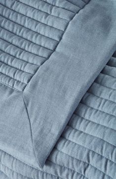 a close up view of a bed with blue sheets and pillows on top of it