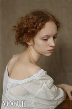 a woman with red hair wearing a white shirt and holding a wooden object in her hand