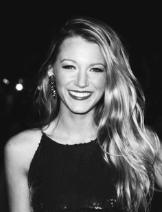 a black and white photo of a woman with long blonde hair smiling at the camera