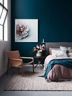 a bedroom with blue walls and pink bedding in the corner, along with two chairs