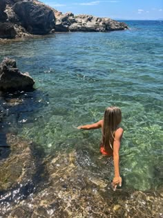 a woman standing in the water near rocks