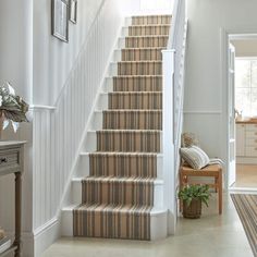 the stairs in this house are lined with carpeted runneres and striped rugs