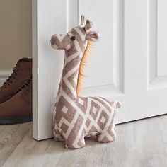 a stuffed giraffe sitting next to a white door