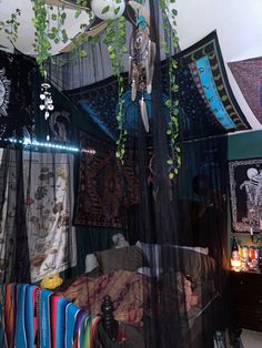 a canopy bed covered in black sheer curtains and hanging art on the wall next to it