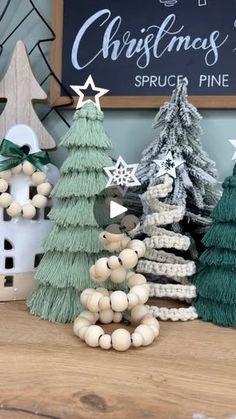 three small christmas trees sitting on top of a wooden table next to a chalkboard