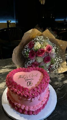 a heart shaped cake sitting on top of a table next to a bouquet of flowers