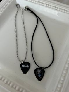 two guitar pick necklaces sitting on top of a white tray