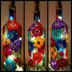 three bottles are decorated with flowers and lights