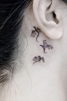 a woman's neck with three small dragon tattoos on it