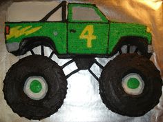 a green monster truck cake with white frosting on it's face and number four