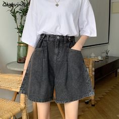 a woman standing in front of a chair with her hands on her hips wearing high waist denim shorts