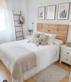 a bed with white linens and pillows in a bedroom next to a wooden ladder