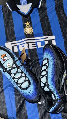 a pair of shoes sitting on top of a blue and black soccer jersey next to a shoe