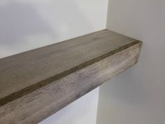 a wooden shelf sitting on top of a wall next to a white wall in a room