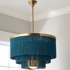 a blue chandelier hanging from the ceiling in a room with white walls and windows