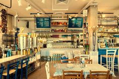 the inside of a restaurant with many tables and chairs in front of shelves filled with bottles