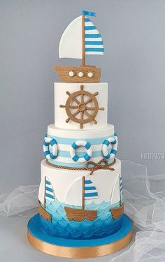 a three tiered cake decorated with blue and white stripes and a ship on top