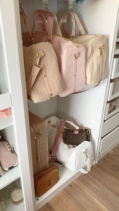 several purses and handbags are hanging on the wall in this closet with white shelving