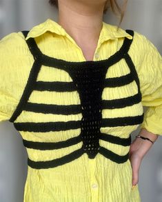 a woman wearing a yellow shirt with black stripes on the front and back, has her hands in her pockets