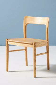 a wooden chair sitting on top of a white floor next to a blue wall in an empty room