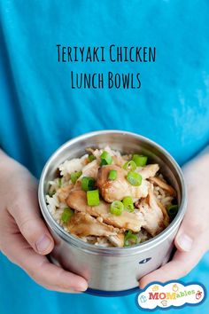 a person holding a metal bowl filled with chicken and green onions on top of rice